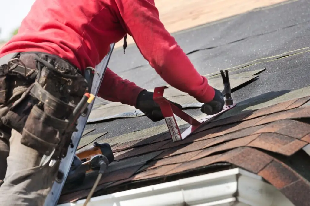 Roofer replacing asphalt shingles on a house roof